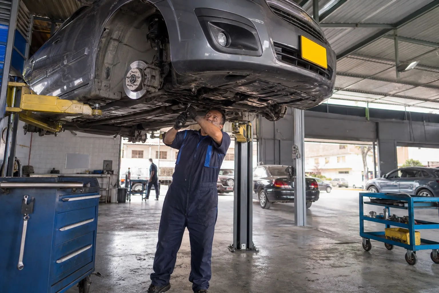 Taller mecánico profesional con auto en elevador y técnico trabajando